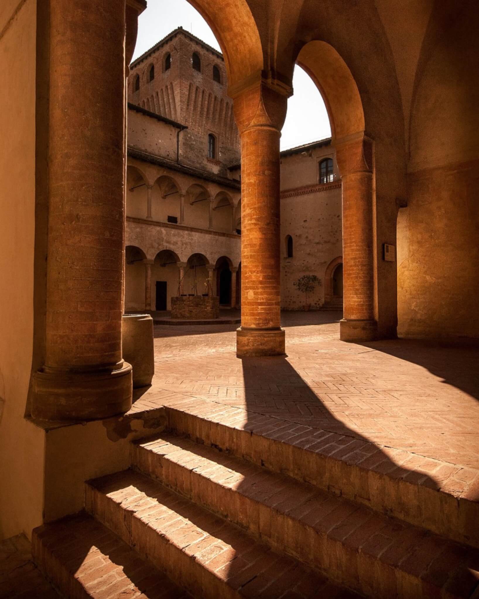Sunlit stone cloister with arches and steps, warm and still